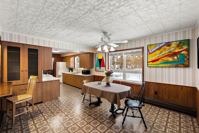 dining room with ceiling fan, wooden walls, sink, and a baseboard heating unit