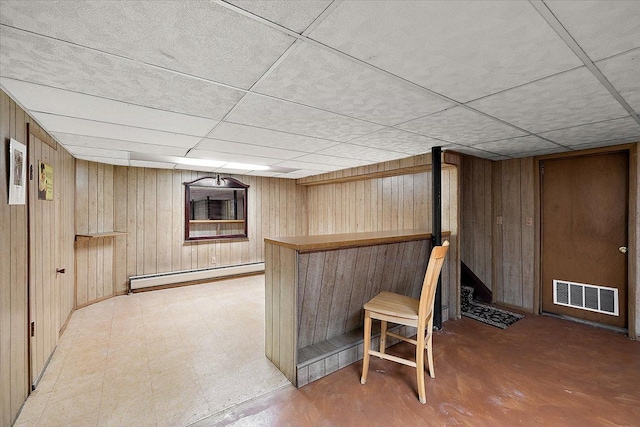 bar with a drop ceiling, wood walls, and baseboard heating