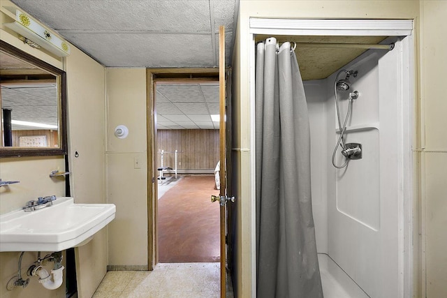 bathroom with wooden walls, a shower, and a baseboard heating unit