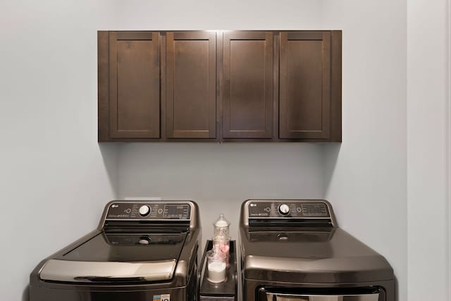 clothes washing area featuring washing machine and dryer and cabinets