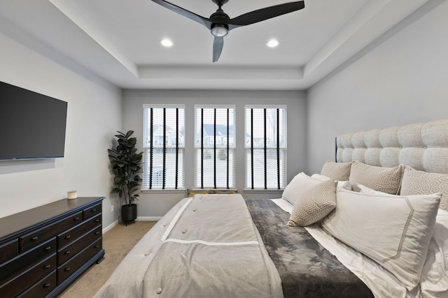 bedroom featuring a tray ceiling, ceiling fan, a water view, and light carpet