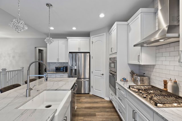 kitchen featuring white cabinetry, sink, wall chimney range hood, tasteful backsplash, and appliances with stainless steel finishes