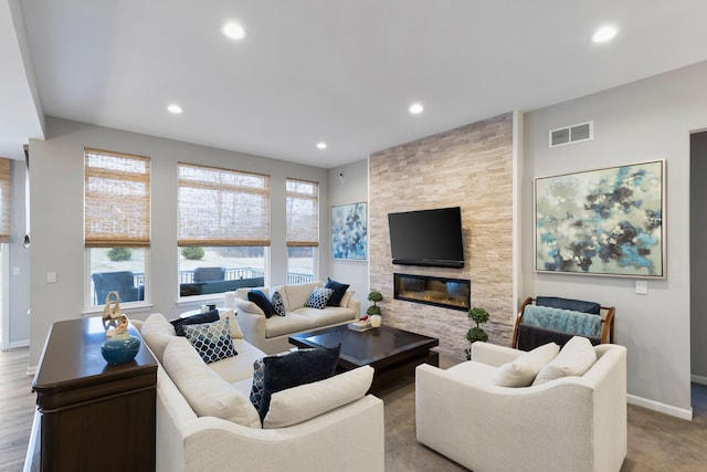 living room featuring a stone fireplace and a healthy amount of sunlight