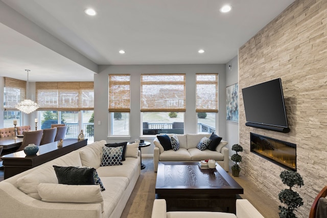 living room featuring hardwood / wood-style flooring, a stone fireplace, and a chandelier