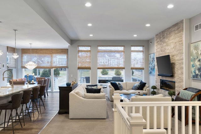 living room with a chandelier, wood-type flooring, a fireplace, and a healthy amount of sunlight