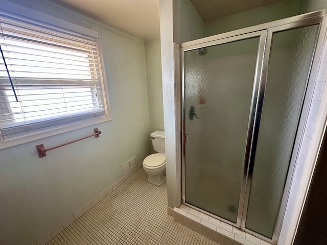 bathroom with tile patterned floors, toilet, and a shower with door