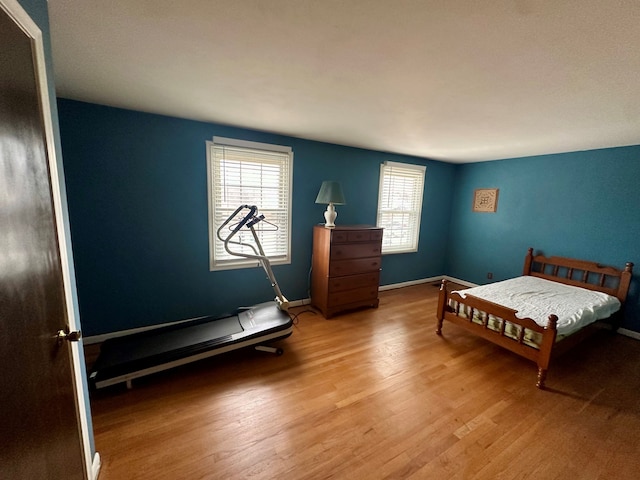 bedroom featuring hardwood / wood-style flooring and a baseboard heating unit