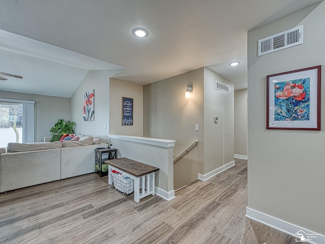 corridor featuring vaulted ceiling and light hardwood / wood-style flooring