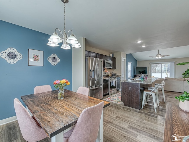 dining room with lofted ceiling, sink, light hardwood / wood-style floors, and ceiling fan with notable chandelier