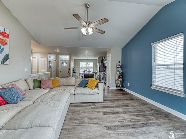 living room with ceiling fan, vaulted ceiling, and light wood-type flooring