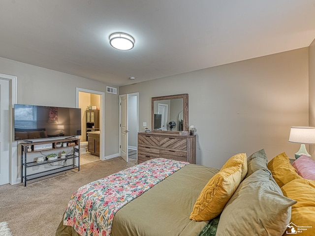 bedroom featuring connected bathroom and light colored carpet