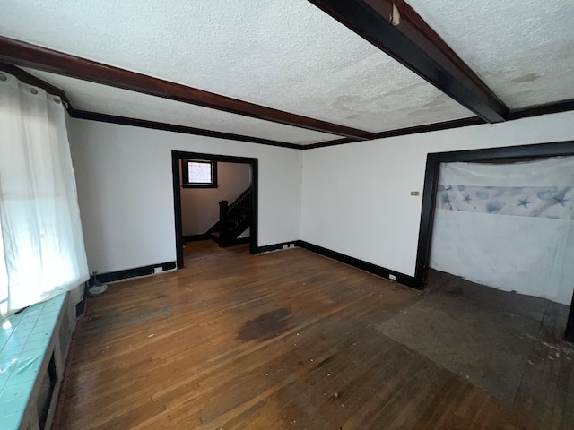 unfurnished room featuring beam ceiling, dark hardwood / wood-style flooring, and a textured ceiling