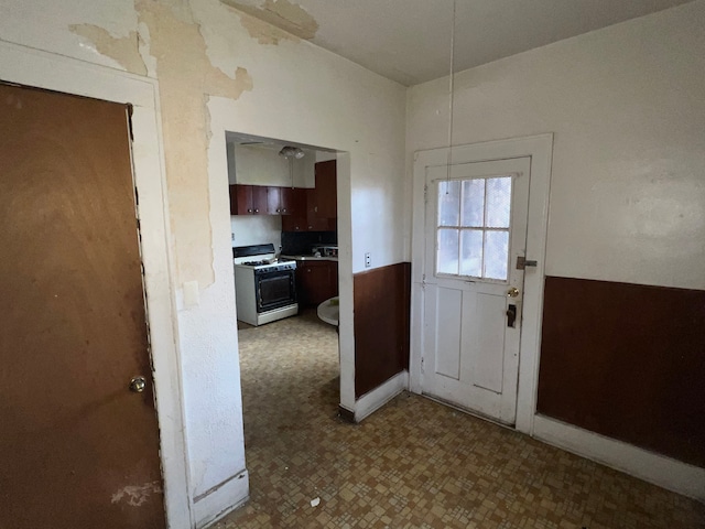 doorway to outside with tile patterned floors and a wainscoted wall