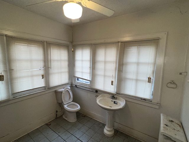 bathroom featuring tile patterned floors, toilet, baseboards, and a sink