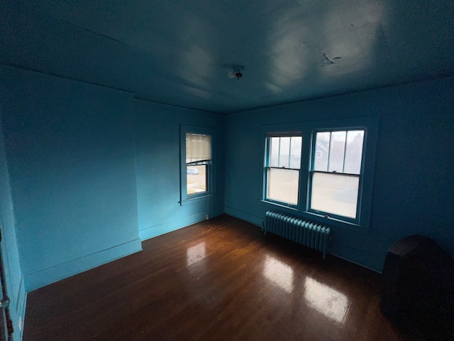 spare room with dark hardwood / wood-style flooring and radiator