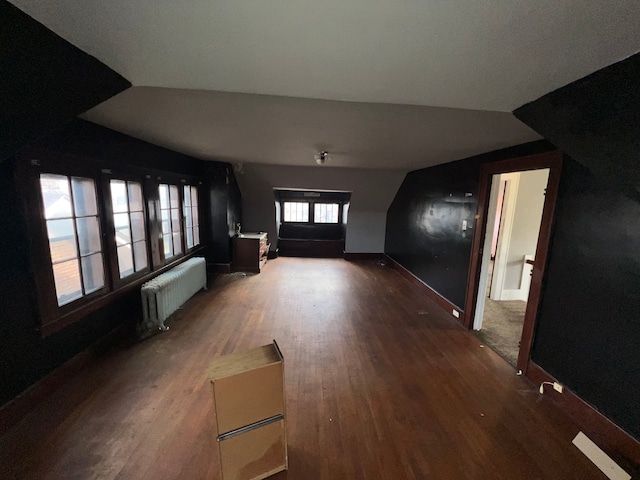 unfurnished living room with hardwood / wood-style flooring, radiator, and lofted ceiling