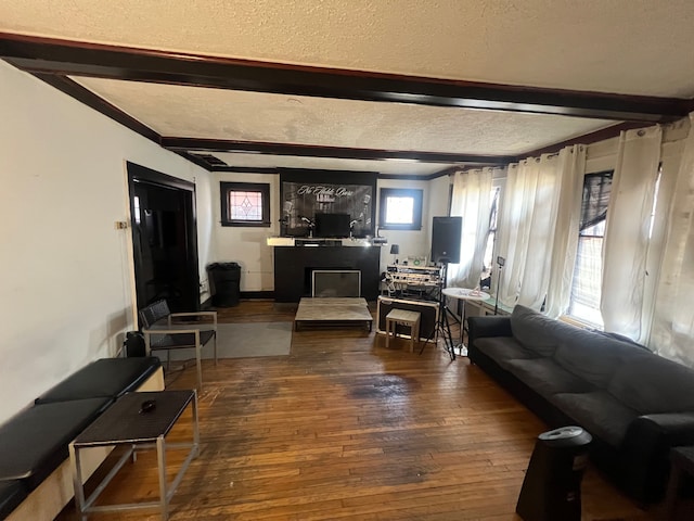 living room with beam ceiling, a textured ceiling, hardwood / wood-style floors, and a fireplace