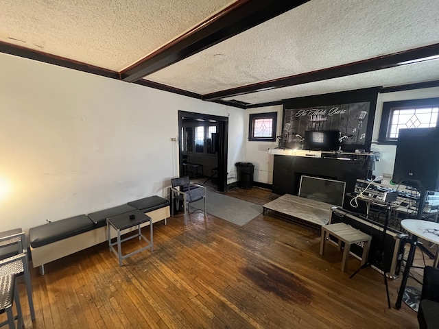 living area with baseboards, a fireplace, hardwood / wood-style flooring, a textured ceiling, and beamed ceiling