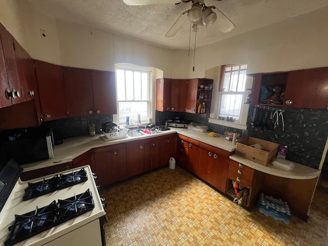 kitchen with white gas stove, a sink, light countertops, and open shelves