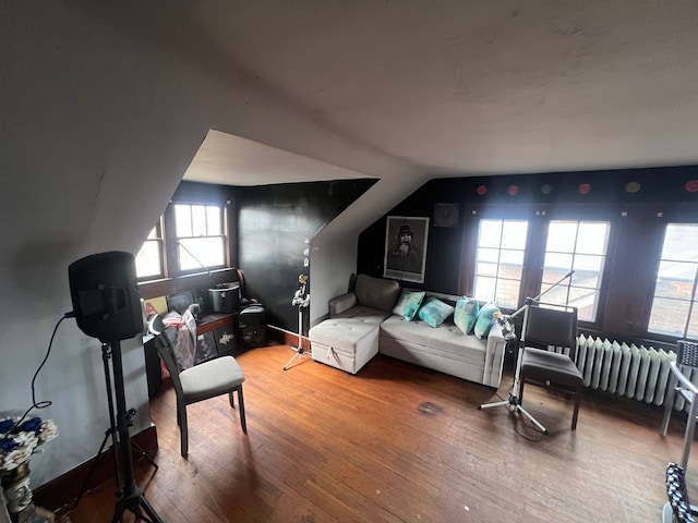 interior space with lofted ceiling, radiator, and hardwood / wood-style floors