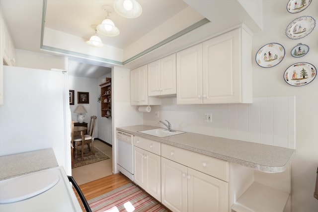 kitchen with sink, backsplash, light hardwood / wood-style floors, white appliances, and white cabinets