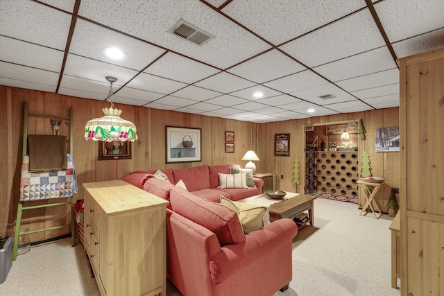 living room featuring a paneled ceiling, light carpet, and wooden walls