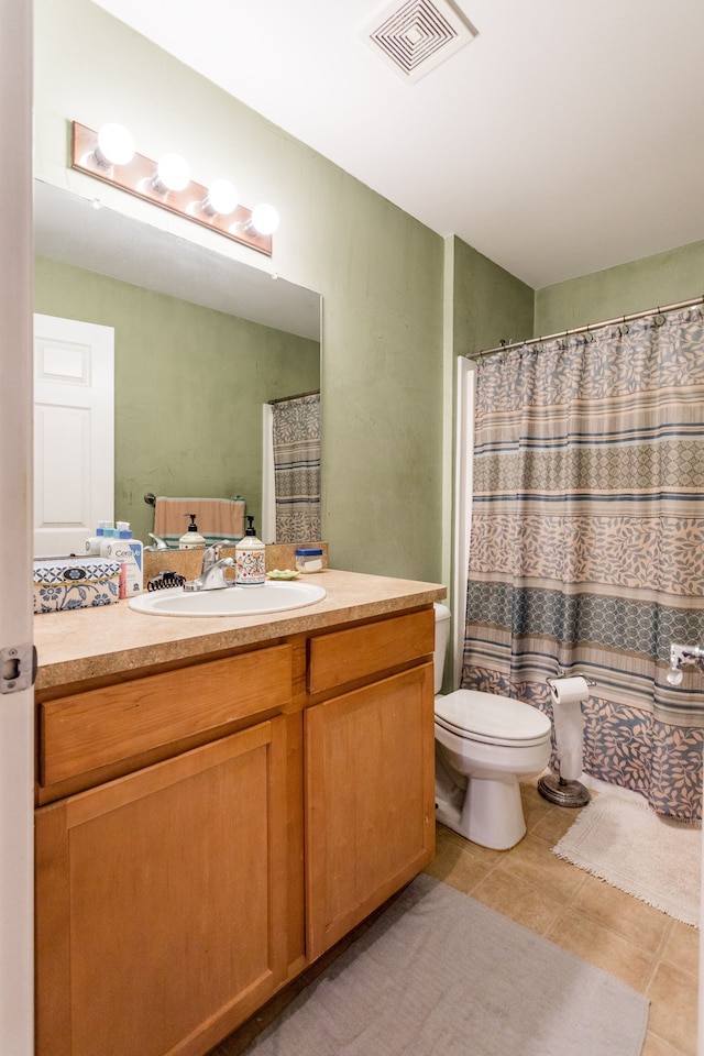 bathroom featuring tile patterned flooring, vanity, toilet, and walk in shower