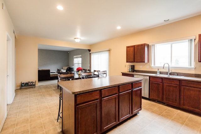 kitchen with a kitchen bar, a center island, stainless steel dishwasher, and sink