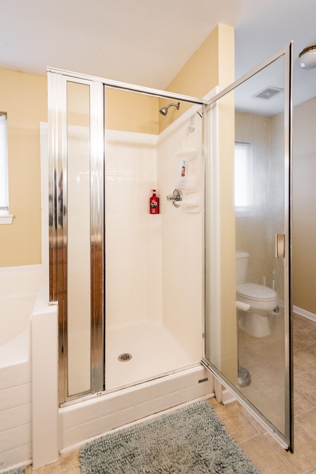 bathroom featuring tile patterned floors, toilet, and a shower with door