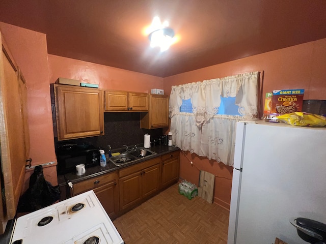 kitchen featuring stove, backsplash, light parquet floors, sink, and white fridge