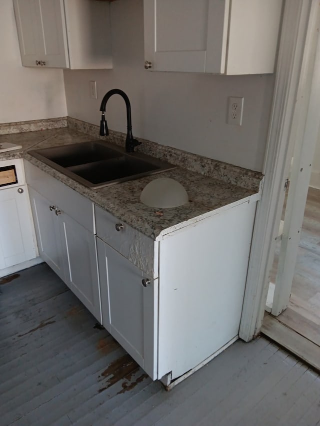 kitchen with sink, stone countertops, white cabinets, and light wood-type flooring