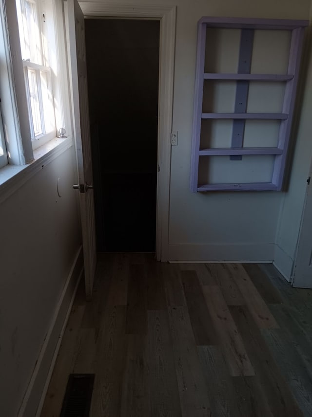 hall featuring built in shelves and dark hardwood / wood-style floors