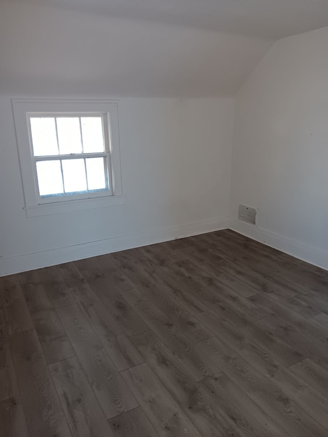 spare room featuring dark hardwood / wood-style flooring and vaulted ceiling