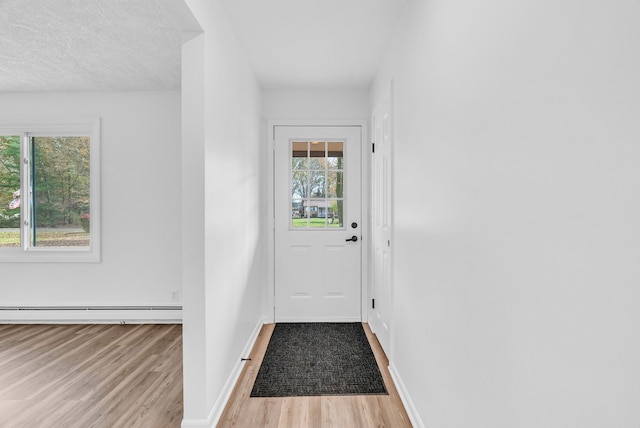 doorway featuring a textured ceiling, light hardwood / wood-style floors, and a baseboard radiator