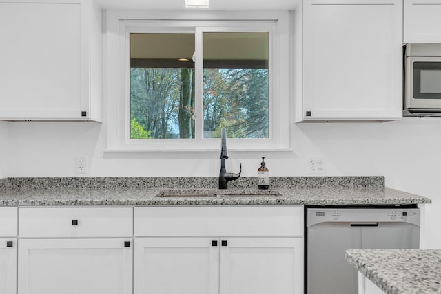 kitchen with light stone counters, sink, white cabinets, and stainless steel appliances