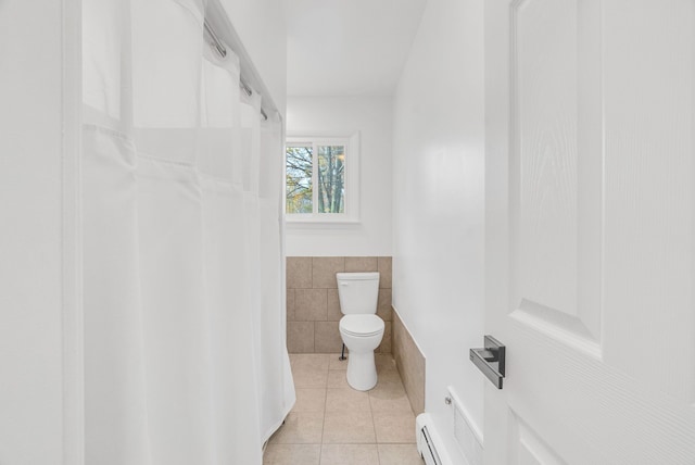 bathroom with tile patterned floors, toilet, baseboard heating, and tile walls