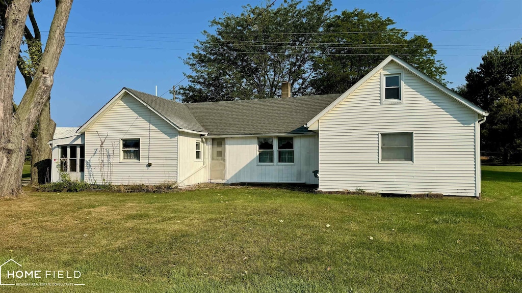 rear view of property featuring a lawn