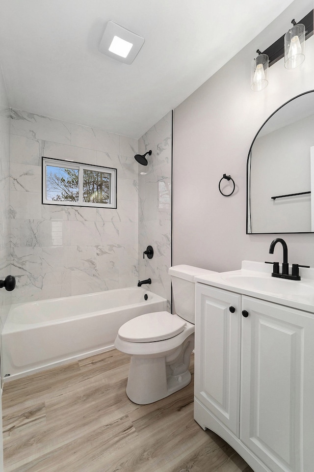 full bathroom with vanity, hardwood / wood-style floors, tiled shower / bath combo, and toilet