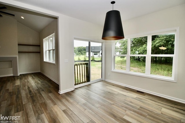 unfurnished dining area featuring wood finished floors, baseboards, ceiling fan, and lofted ceiling