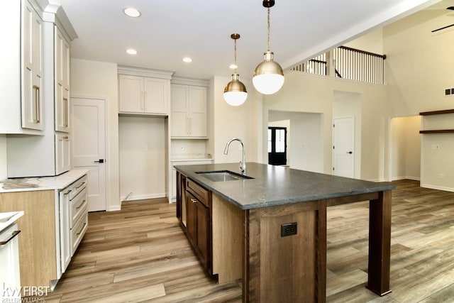 kitchen featuring a sink, light wood finished floors, baseboards, hanging light fixtures, and recessed lighting