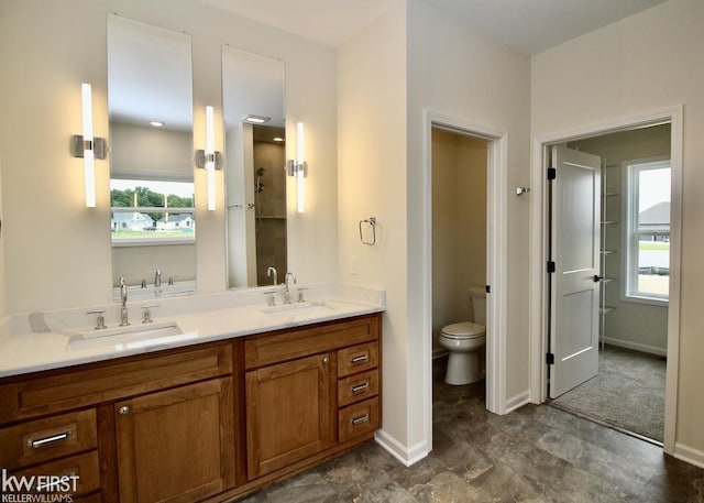 bathroom with toilet, baseboards, and double vanity