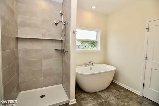 bathroom featuring a tile shower, baseboards, and a soaking tub