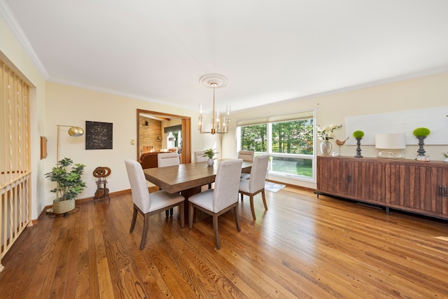 dining room with ornamental molding, a notable chandelier, and hardwood / wood-style flooring