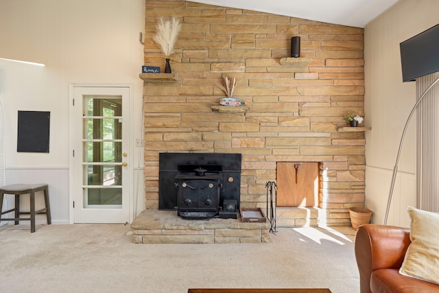 living room featuring a wood stove, carpet floors, and lofted ceiling