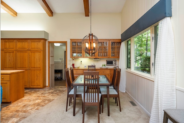 dining room featuring beam ceiling, wood walls, and an inviting chandelier