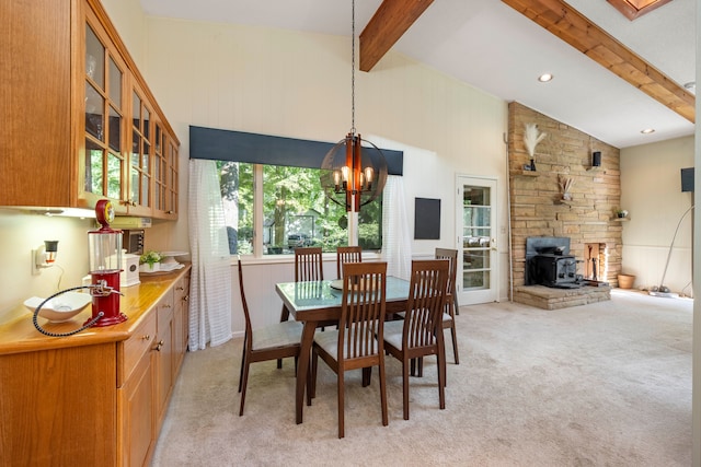 dining room with lofted ceiling with beams, a wood stove, light carpet, and a chandelier