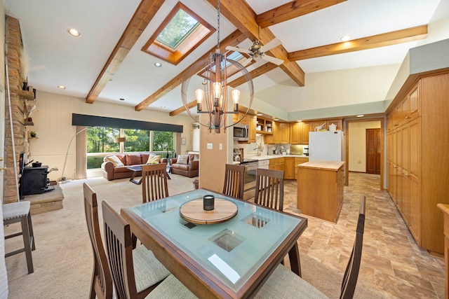 dining room featuring lofted ceiling with skylight, sink, light colored carpet, and ceiling fan with notable chandelier