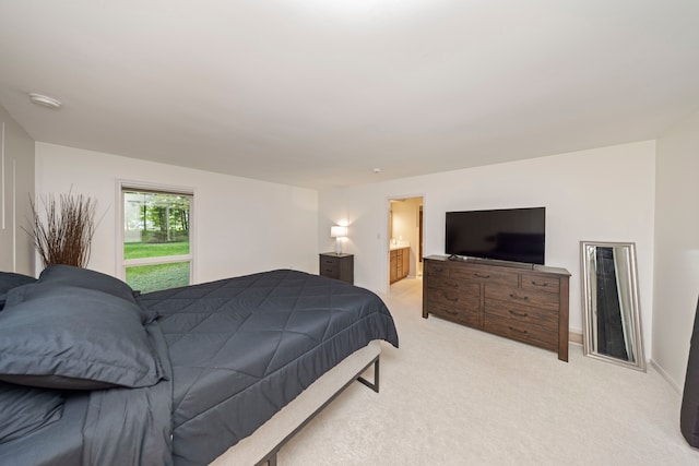 bedroom with ensuite bath and light carpet