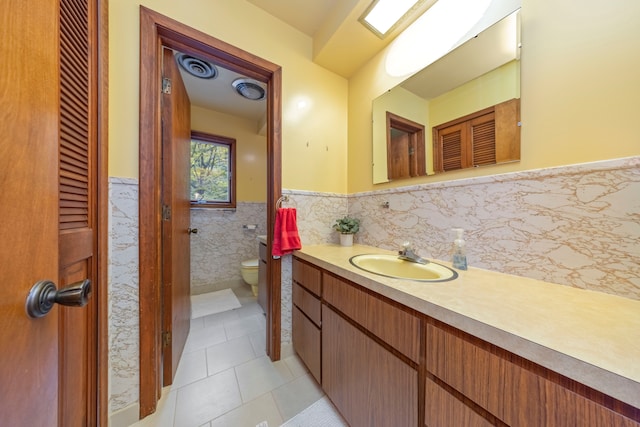 bathroom featuring tile patterned flooring, vanity, tile walls, and toilet