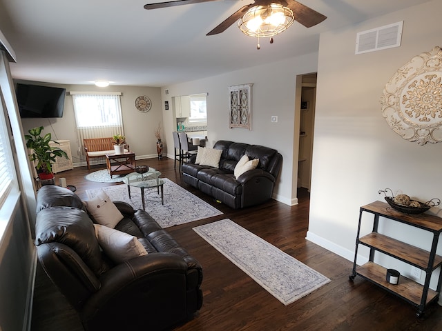 living room featuring ceiling fan and dark wood-type flooring